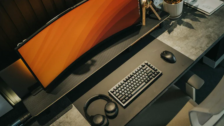 Ultrawide monitor, keyboard, mouse, and headphones on a premium desk setup.