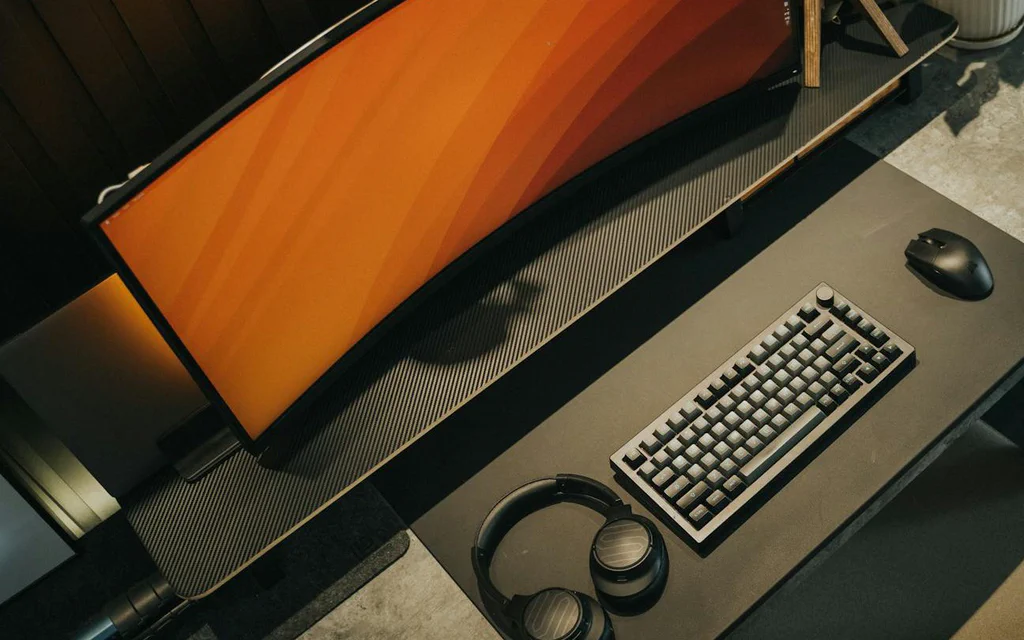 Ultrawide monitor, keyboard, mouse, and headphones on a premium desk setup.