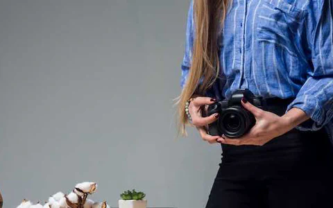 A person holding their first mirrorless camera, looking thoughtfully at the settings before taking a photo.