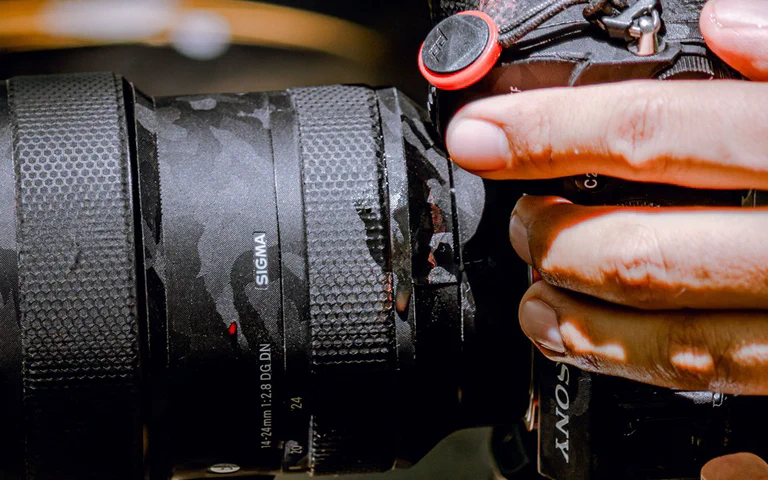 Hands adjusting a mirrorless camera outdoors before taking a photo.
