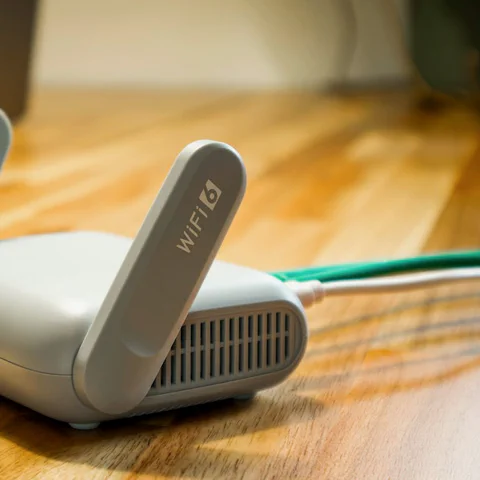 Домашний Wi-Fi-роутер крупным планом на столе с подключенным Ethernet-кабелем.