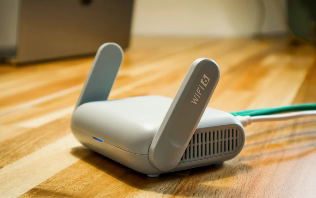 Close-up of a home Wi-Fi router on a desk with an Ethernet cable connected.