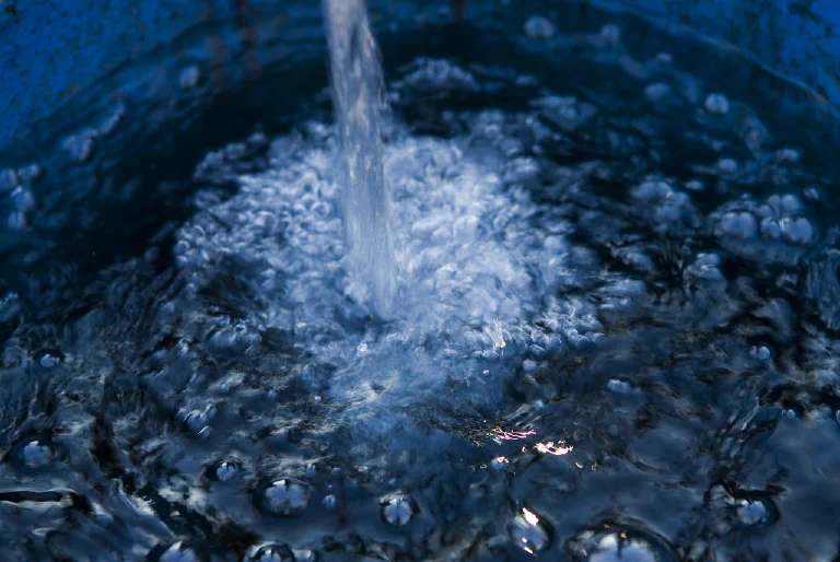 A person pouring fresh water into their home humidifier.