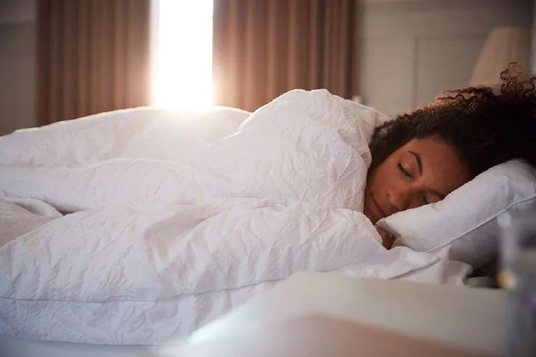 A woman sleeping peacefully in a comfortable bedroom.