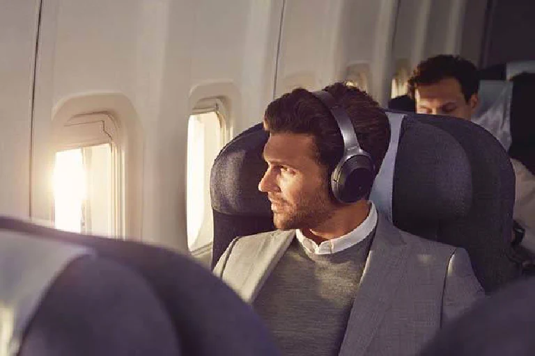 A person wearing Bose noise-canceling headphones on a plane, looking out the window.