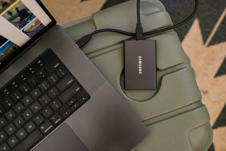 Portable external SSD connected to a laptop for file backup and storage planning.