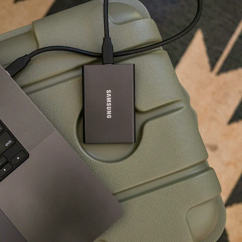 Portable external SSD connected to a laptop for file backup and storage planning.