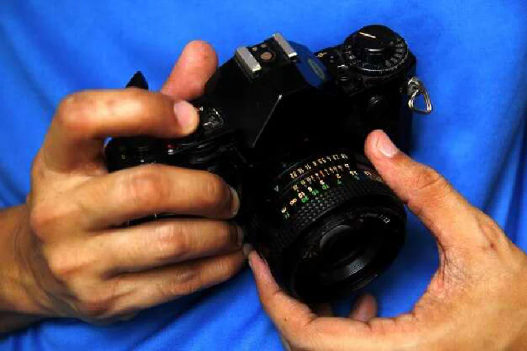 A person holding a modern mirrorless camera, ready to take a picture in a scenic location.