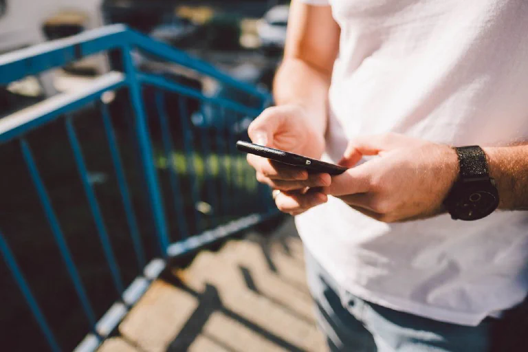 A person's hands holding a smartphone, editing a vibrant landscape photo using a mobile app.