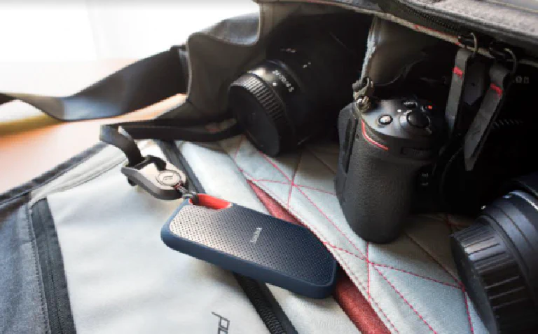 The SanDisk Extreme Portable SSD with its distinctive carabiner loop, clipped to a backpack.