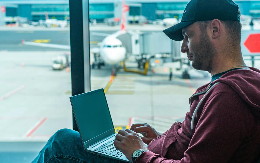 Traveler using a laptop at an airport before choosing a VPN service.
