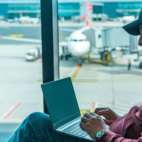 Traveler using a laptop at an airport before choosing a VPN service.