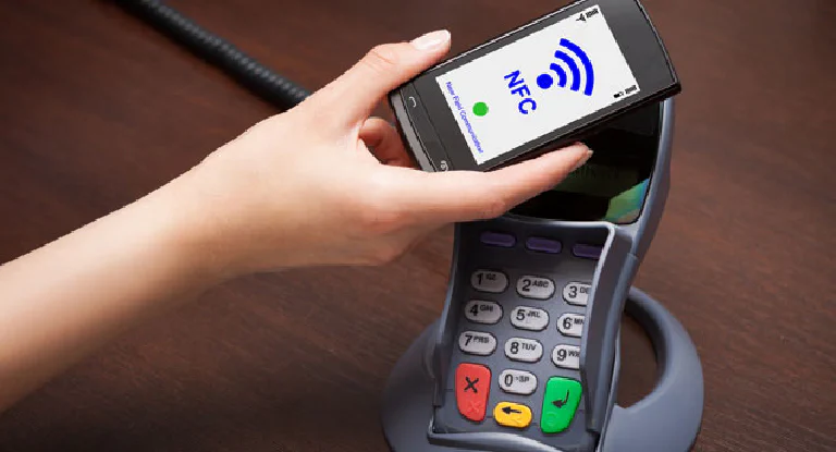 A person holding a smartphone near a payment terminal, illustrating a successful NFC contactless payment.