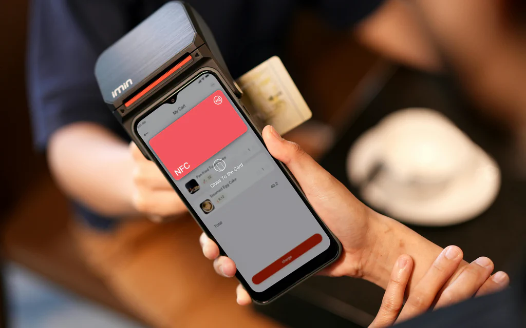 A smartphone held near a payment terminal during an NFC contactless payment.