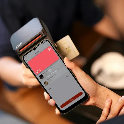 A smartphone held near a payment terminal during an NFC contactless payment.